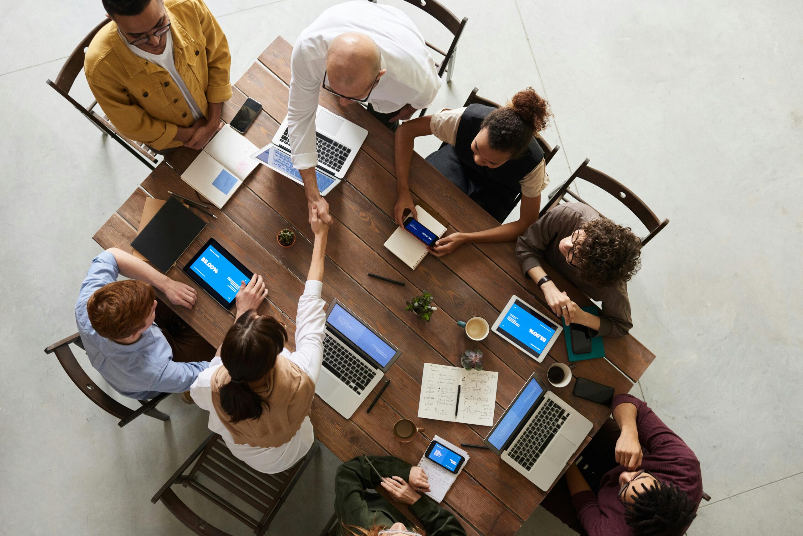 cozy-place Top view of a diverse team collaborating in an office setting with laptops and tablets, promoting cooperation.